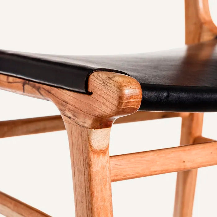 Silla color negro, fabricada en madera maciza de teca color natural y piel.