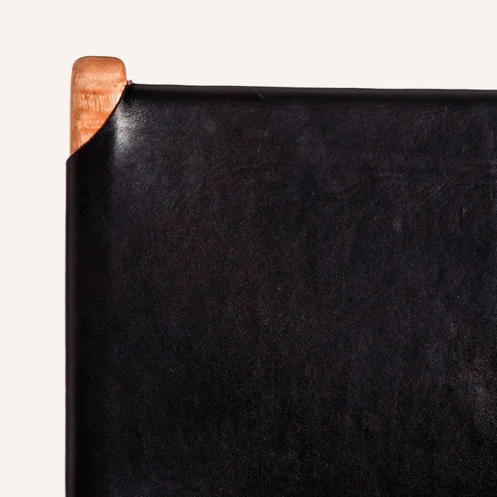 Silla color negro, fabricada en madera maciza de teca color natural y piel.