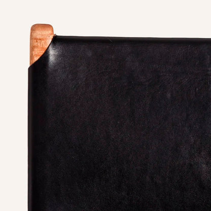 Silla color negro, fabricada en madera maciza de teca color natural y piel.