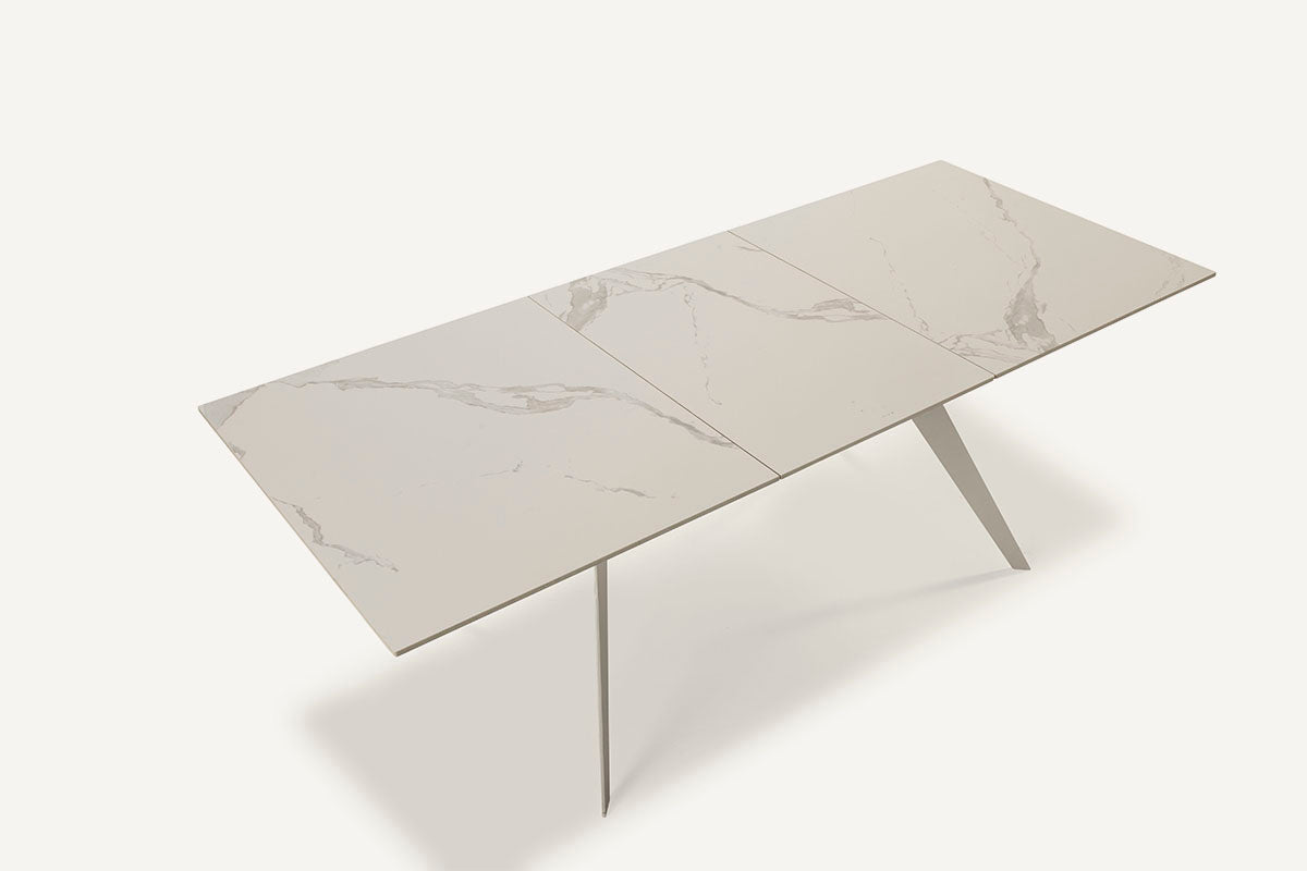 Mesa comedor Lula, rectangular y extensible, en color blanco con pie metálico blanco. Fabricada de cerámica y metal.