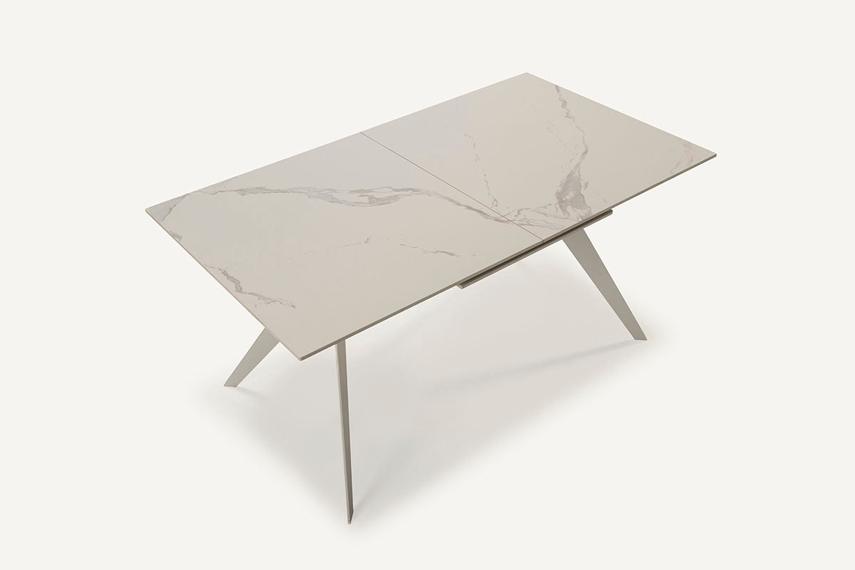 Mesa comedor Lula, rectangular y extensible, en color blanco con pie metálico blanco. Fabricada de cerámica y metal.