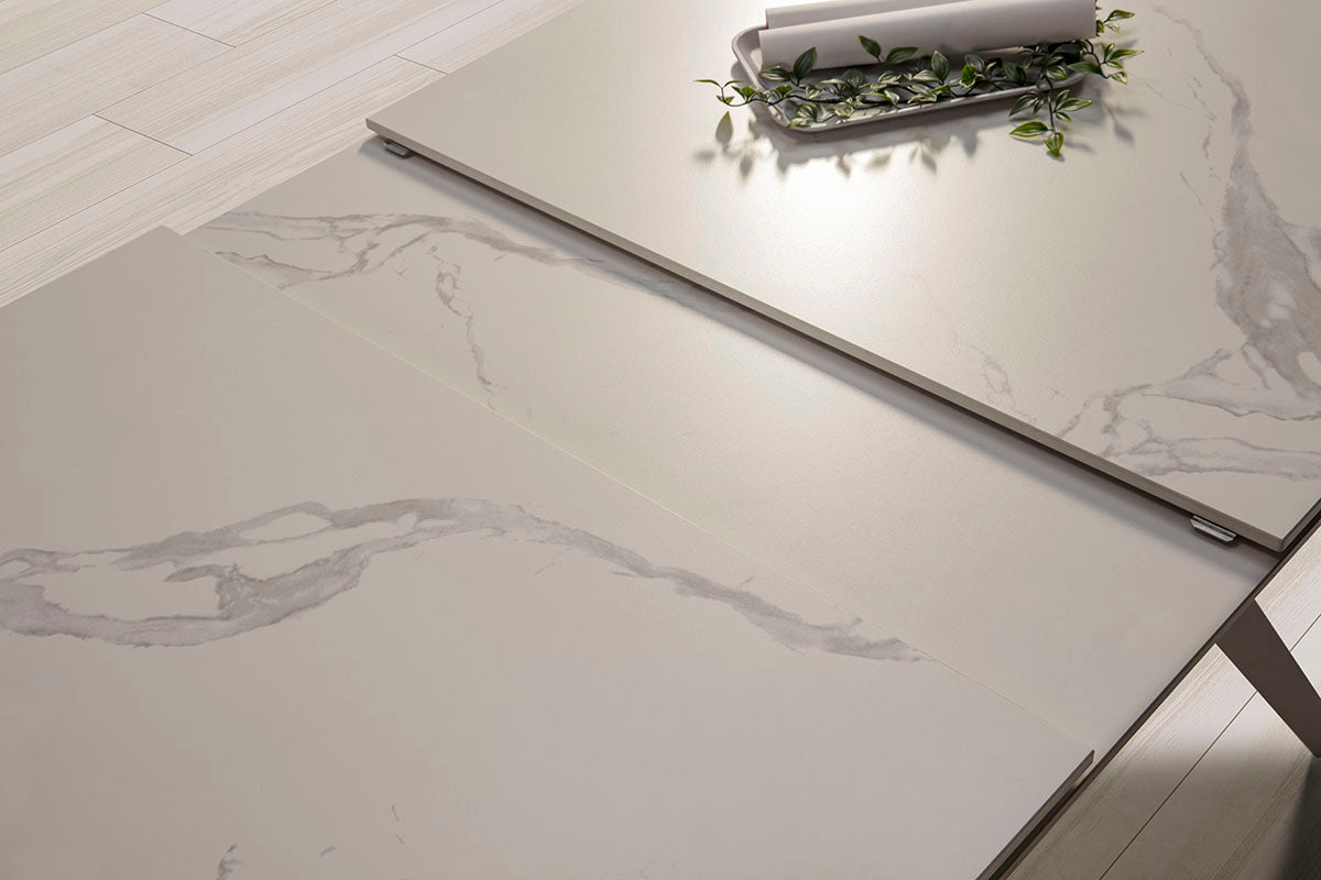 Mesa comedor Lula, rectangular y extensible, en color blanco con pie metálico blanco. Fabricada de cerámica y metal.