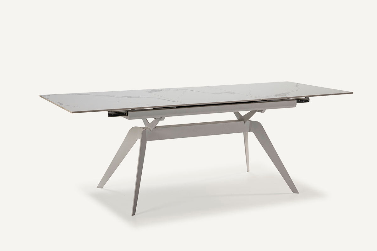 Mesa comedor Lula, rectangular y extensible, en color blanco con pie metálico blanco. Fabricada de cerámica y metal.
