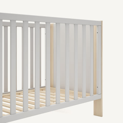 Detalle de cuna de bebé con barrotes y acabado en blanco y madera