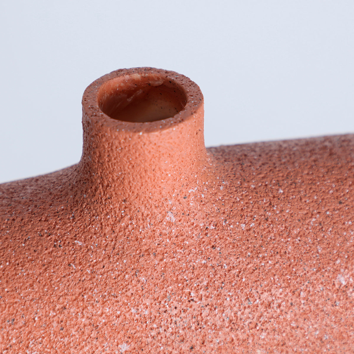 Jarrón en color terracota con acabado rugoso, fabricado de resina.