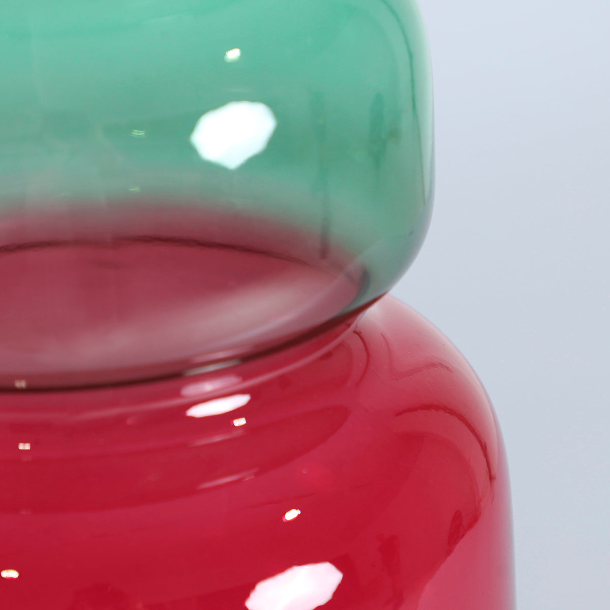 Jarrón en color verde y rosa fucsia con acabado traslúcido, fabricado de cristal.
