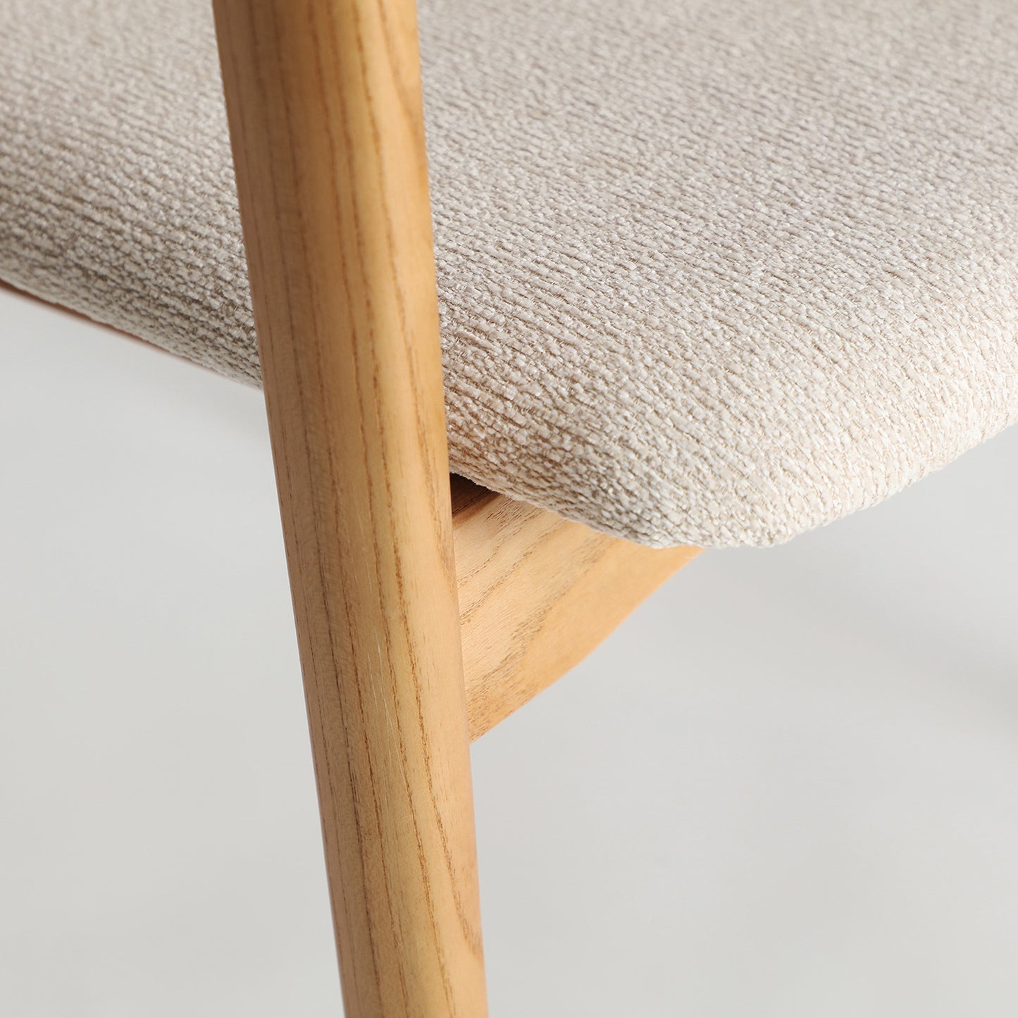 Detalle de silla Eriswil con estructura de madera y asiento acolchado claro