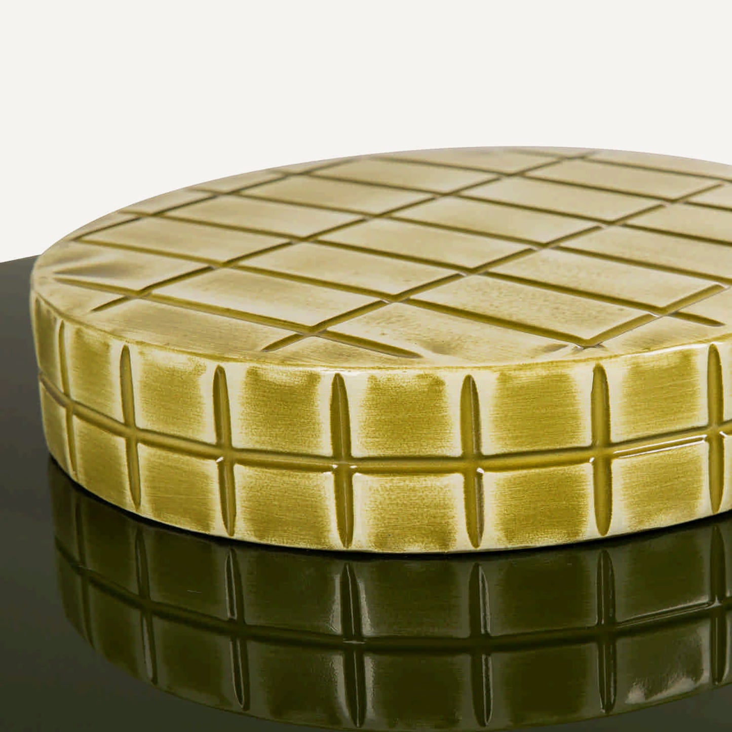 Mesa auxiliar ovalada con pie circular en metal tallado en cuadros verde amarillo.