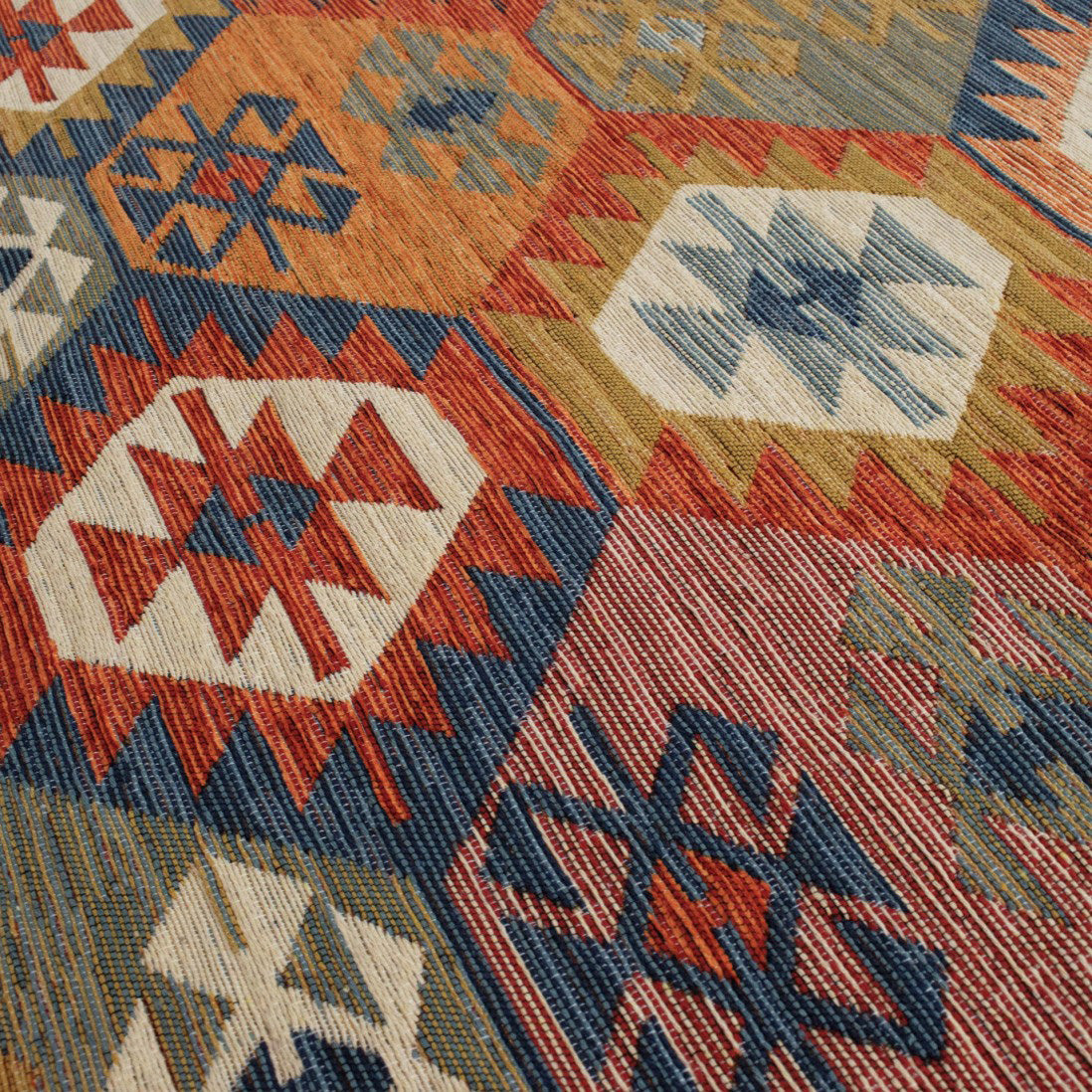 Alfombra Kilim con tonalidades de colores terrosos y un dibujo geométrico.