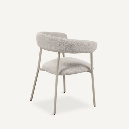 Silla que combina diseño y funcionalidad, con asiento tapizado en color gris, respaldo redondeado al aire y patas en metal crema.