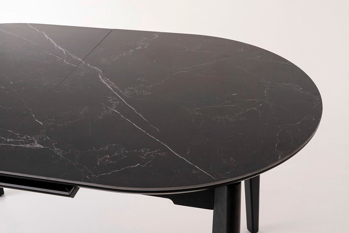 Mesa de comedor ovalada y extensible, en color negro con vetas blancas. Fabricada de metal combinada con tapa de porcelánico negro.