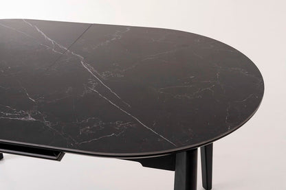 Mesa de comedor ovalada y extensible, en color negro con vetas blancas. Fabricada de metal combinada con tapa de porcelánico negro.