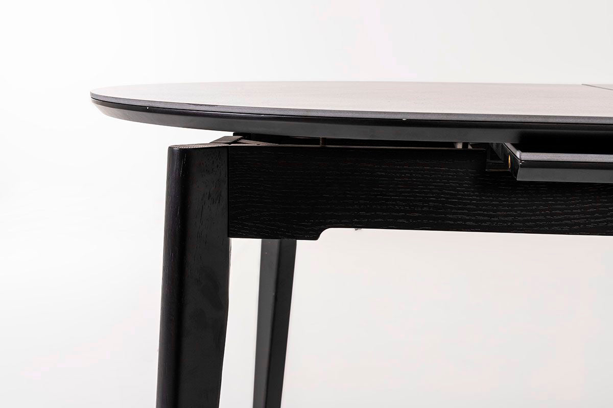 Mesa de comedor ovalada y extensible, en color negro con vetas blancas. Fabricada de metal combinada con tapa de porcelánico negro.