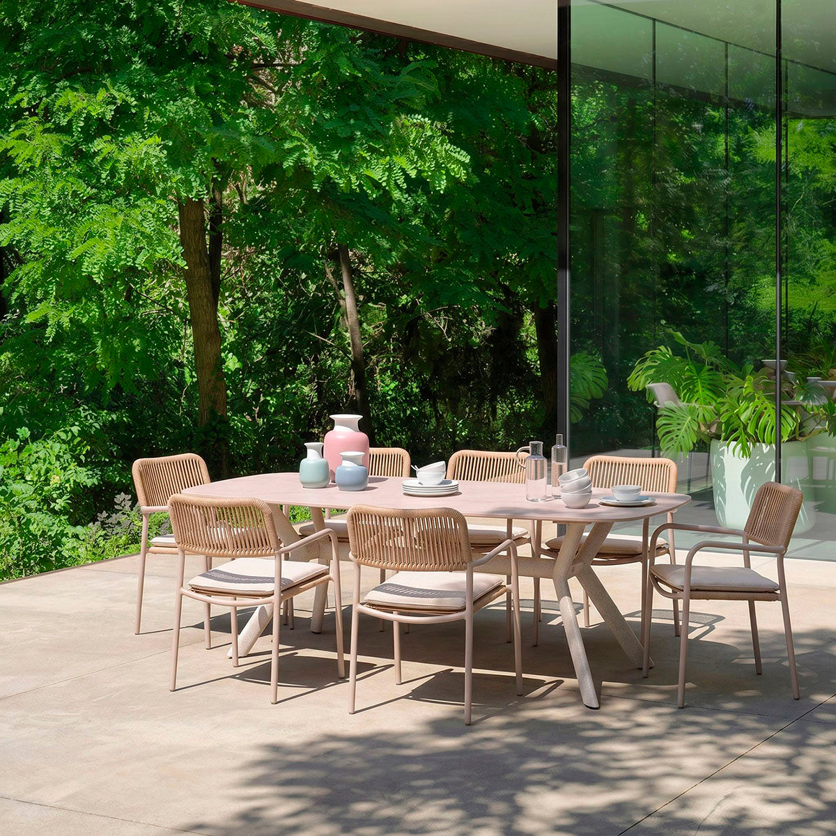 Mesa de comedor outdoor, con un diseño minimalista. Fabricada de metal con tapa de porcelánico ovalada en color beige con pequeñas vetas.