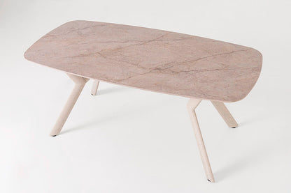 Mesa de comedor outdoor, con un diseño minimalista. Fabricada de metal con tapa de porcelánico ovalada en color beige con pequeñas vetas.