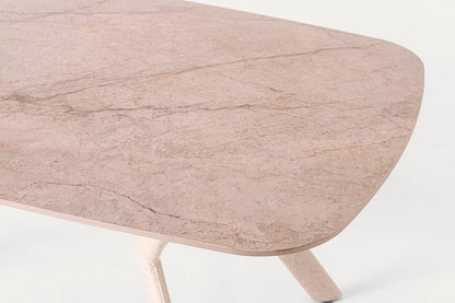 Mesa de comedor outdoor, con un diseño minimalista. Fabricada de metal con tapa de porcelánico ovalada en color beige con pequeñas vetas.