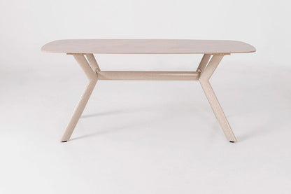 Mesa de comedor outdoor, con un diseño minimalista. Fabricada de metal con tapa de porcelánico ovalada en color beige con pequeñas vetas.